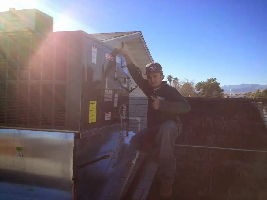 HVAC technician performing Air Duct Repair on a rooftop unit in Chickasaw